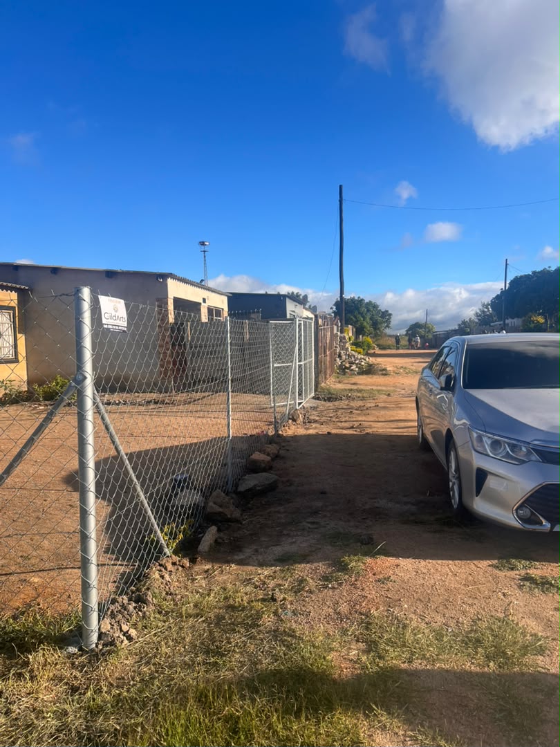 Chain-link driveway fence beside a home installed by GildArts